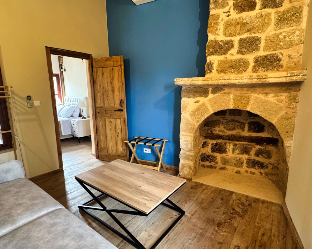Harmonia Junior Suite sitting room with a stone fireplace and blue wall
