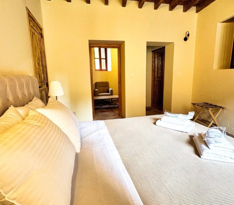 Iris Junior Suite bedroom with an upholstered bed and timber ceiling beams