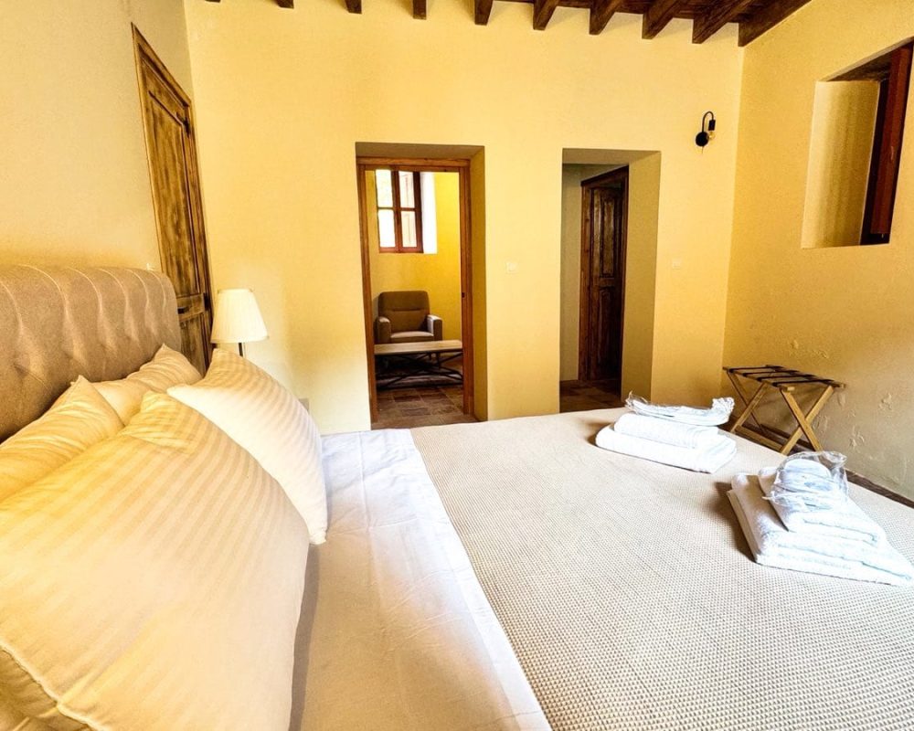 Iris Junior Suite bedroom with an upholstered bed and timber ceiling beams