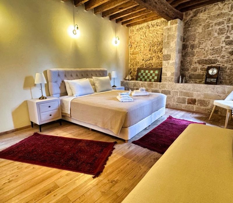 Daphne Junior Suite bedroom with exposed stonework and timber ceiling beams
