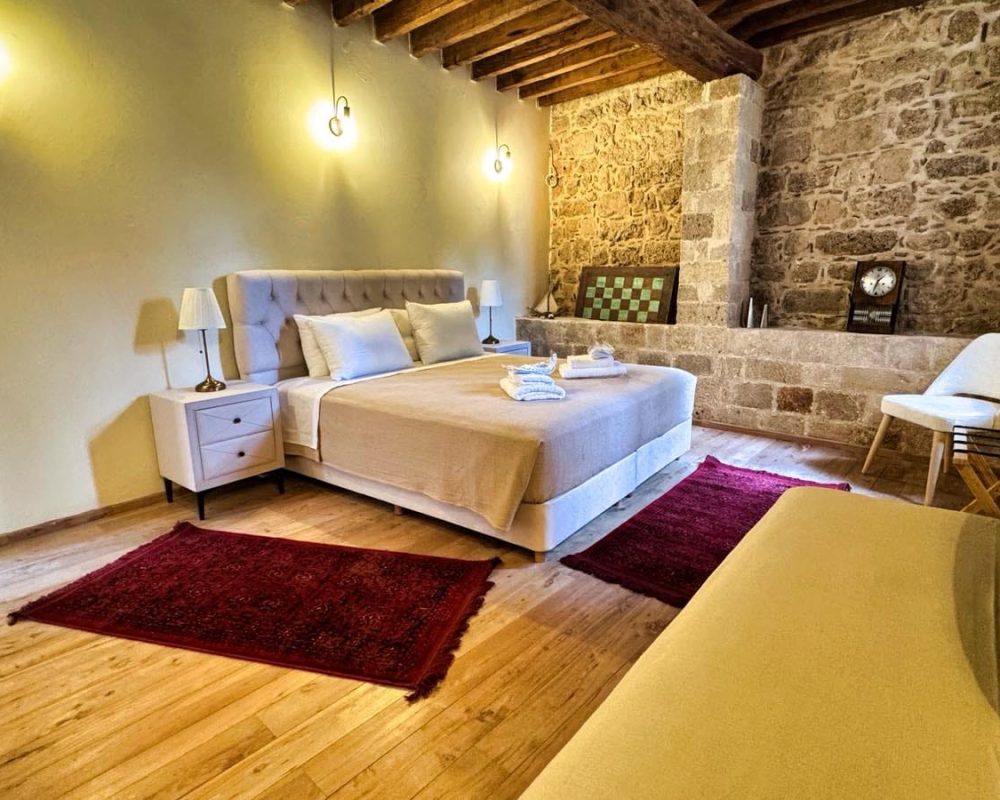 Daphne Junior Suite bedroom with exposed stonework and timber ceiling beams