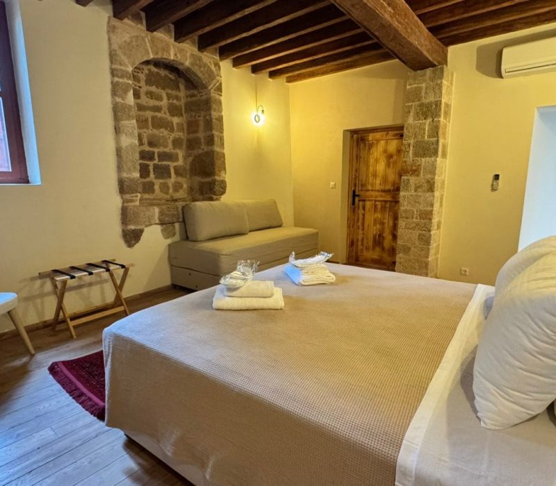 Daphne Junior Suite bedroom with a sofa and exposed stonework