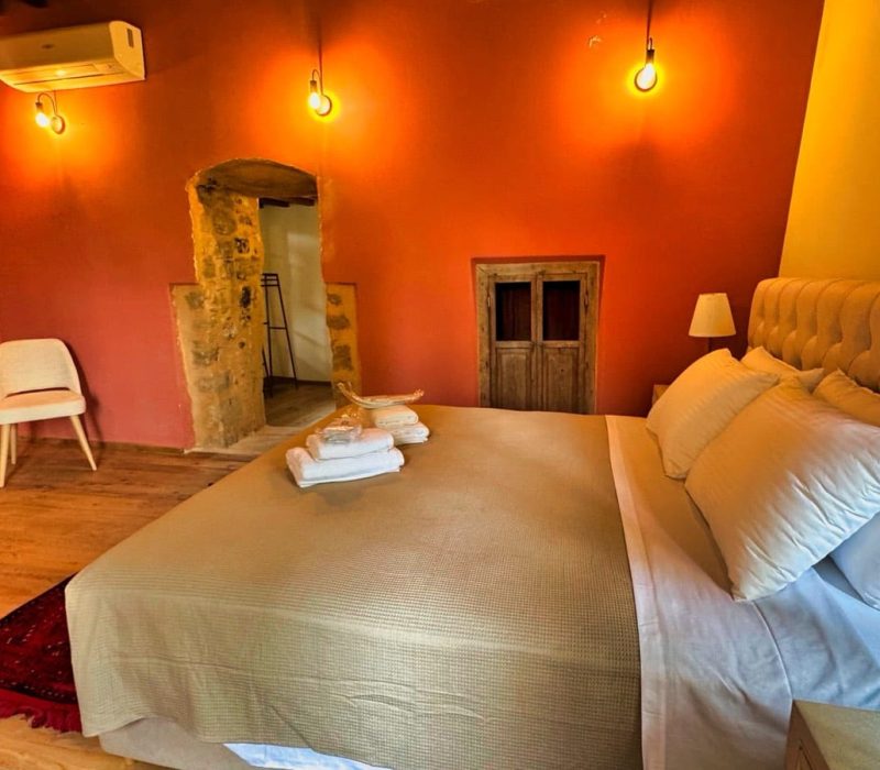Chloe Junior Suite bedroom with an upholstered bed and orange accent wall